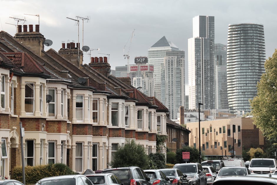 A professional removals team member from Self Storage Islington, wearing dark clothing and red shoes, is inside a bright, spacious room with white walls and large arched windows. He is carrying two me